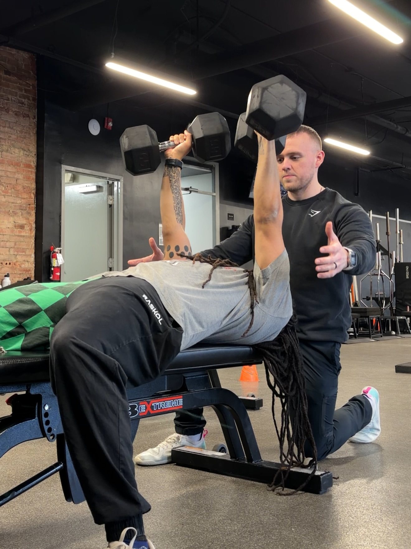 Kevin Rimler coaching a client through a dumbbell press — founder of Tunnel Vision Training